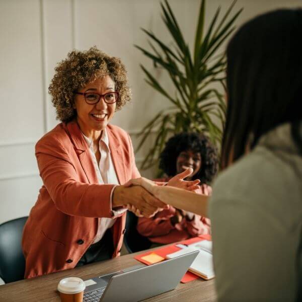 woman reaching over desk happily greeting a colleague